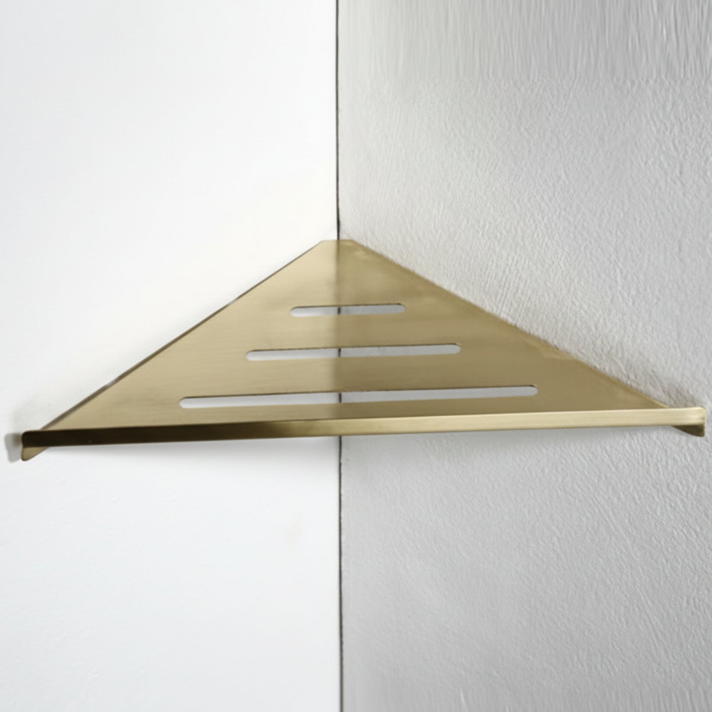 Gold triangular shower shelf mounted on a white wall. Stylish golden bathroom rack. Modern bathroom rack, minimalist and timeless pieces for bathroom.