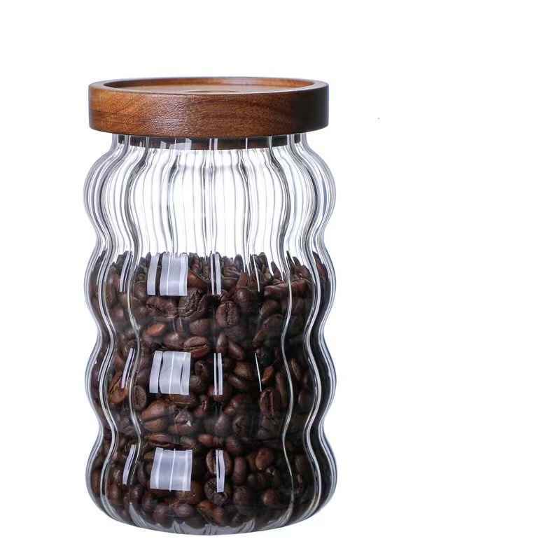 One large glass jar with wooden lid, filled with coffee beans and on a white background. Scandinavian kitchen decor inspired. Simplicity, natural materials, earthy, warm, pure.