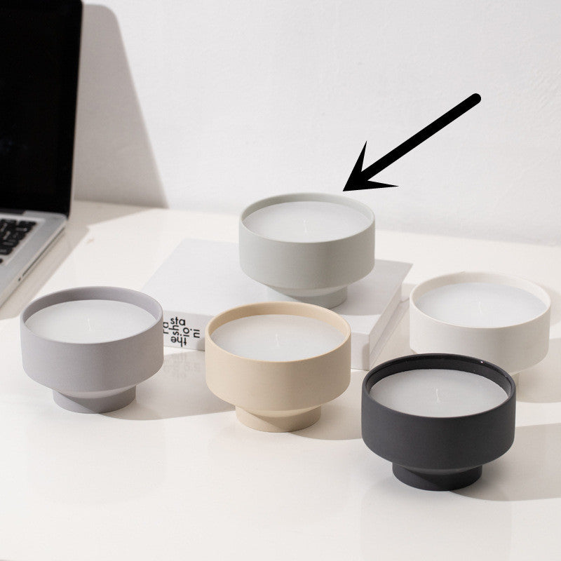 Set of five ceramic bowls in different colors on a white surface on a white wall background. Laptop in the picture. Scandinavian decor simplicity. Light grey candle is in the center.