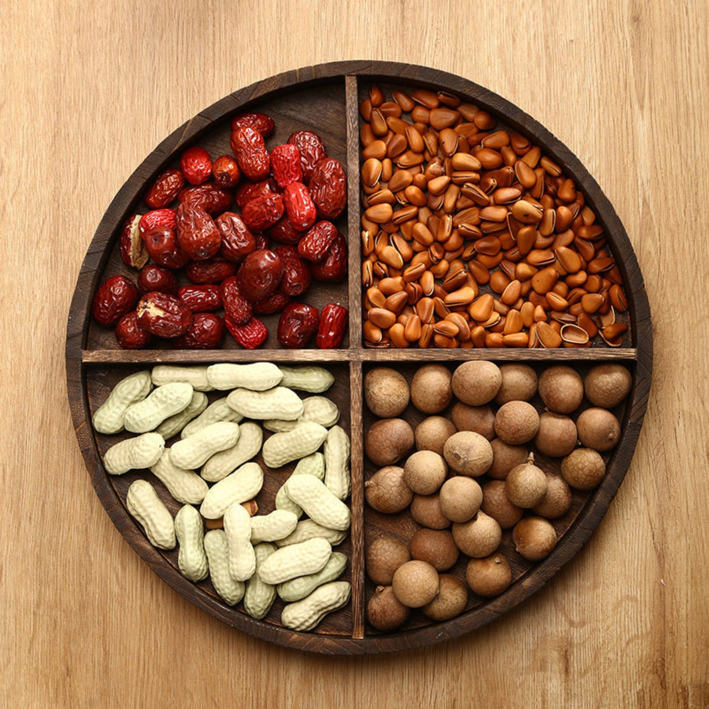 Wooden tray with compartments filled with dried fruits and nuts on a wooden surface. Wooden plate on a table. Natural decor styling ideas for calm and modern kitchen items. Minimalist wooden pieces.