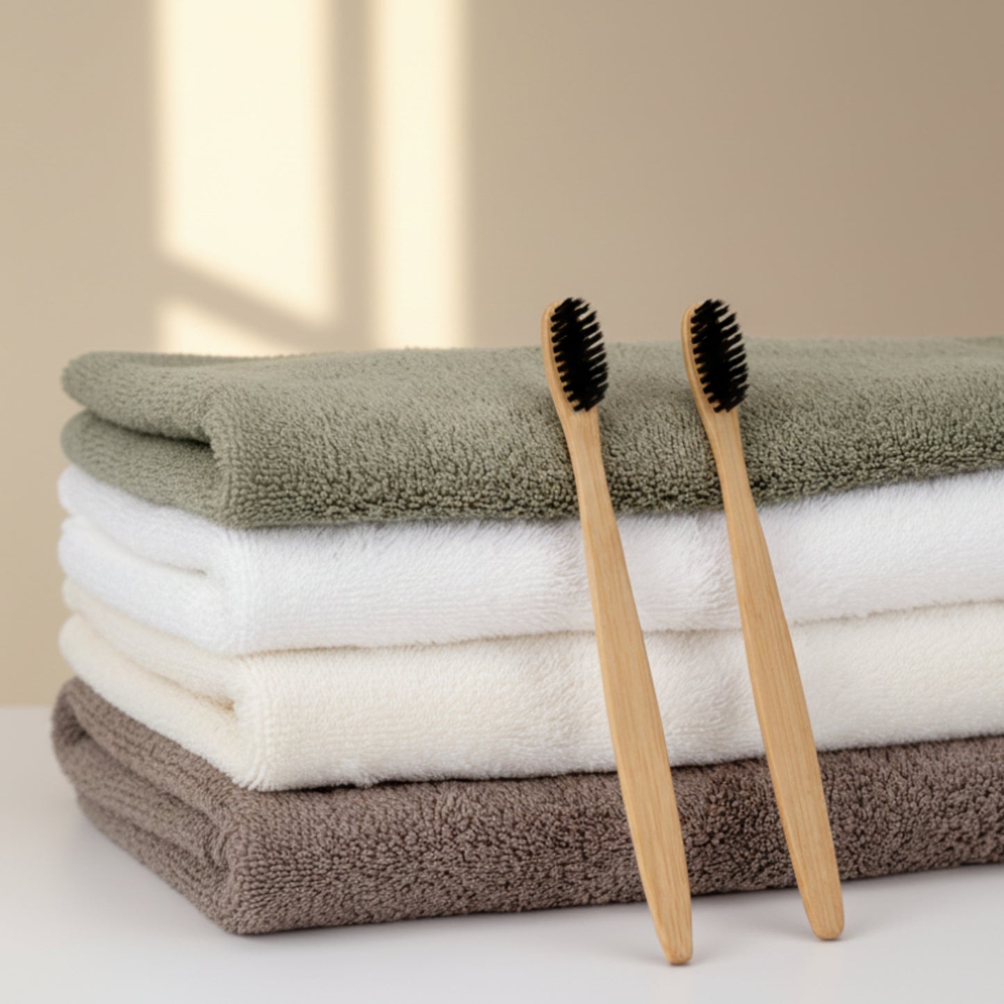 Two bamboo toothbrushes with black bristles on a stack of folded towels. Eco-friendly and anti-bacterial.