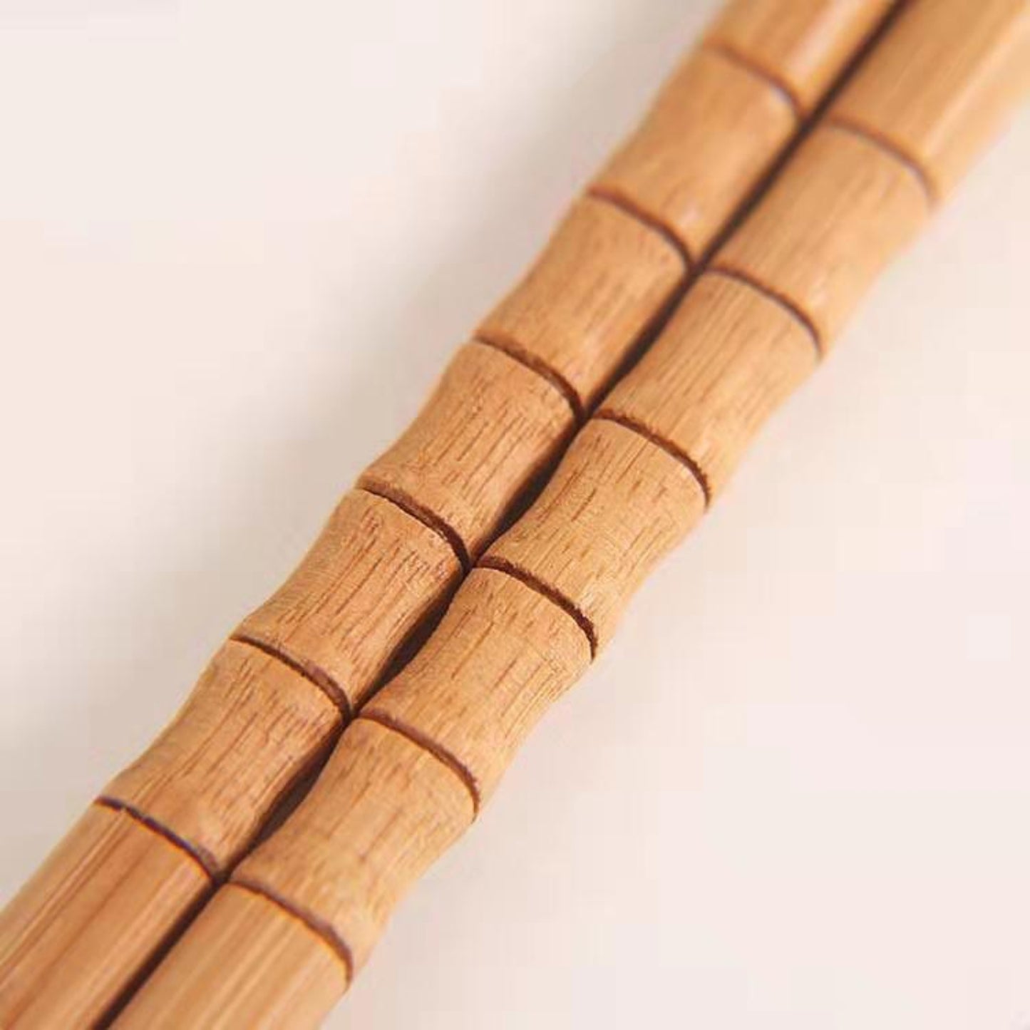 Close-up of one pair of chopsticks on a white surface. Natural, unpainted, eco-friendly bamboo.