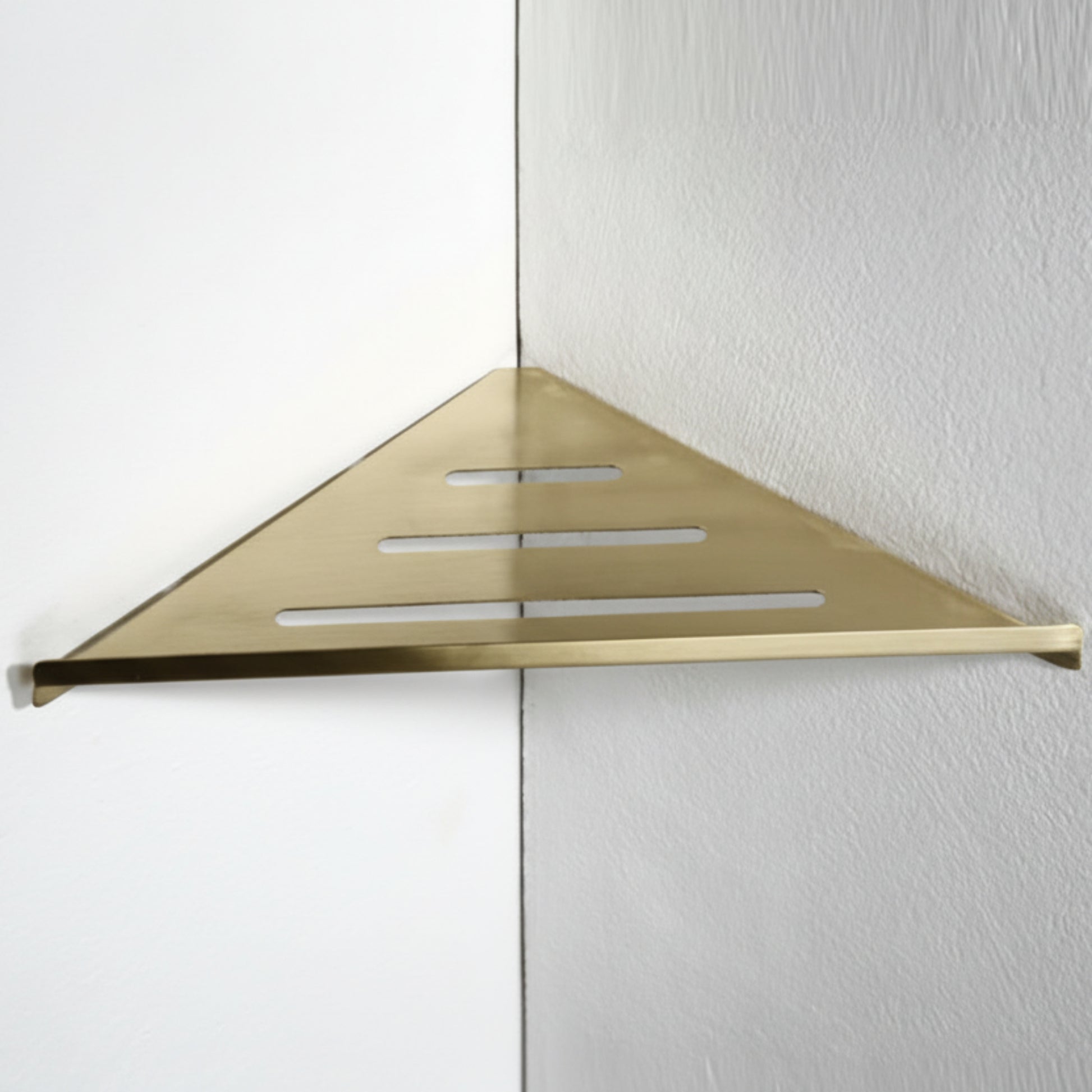 Gold triangular shower shelf mounted on a white wall. Stylish golden bathroom rack. Modern bathroom rack, minimalist and timeless pieces for bathroom. 