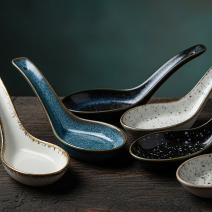 Set of six ceramic spoons with speckled patterns on a dark wooden surface. Set of ceramic spoons with speckled finish on a wooden table and green background. Handcrafted ceramic spoon in different colors. 