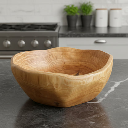 Wooden bowl on a dark gray marble kitchen counter with a blurred kitchen background. Scandinavian earthy natural decor styling. 