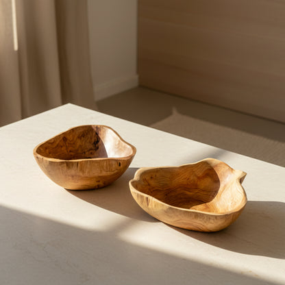 Two wooden bowls on a light surface with a neutral wooden background. Scandinavian earthy natural decor styling. 