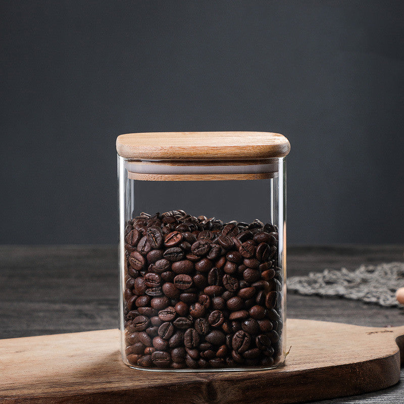 Airtight kitchen jar with wooden lid filled with coffee beans on a wooden kitchen surface on a dark grey background. A warm minimalist interior with simple decor and simple design. Storage kitchen jar. 