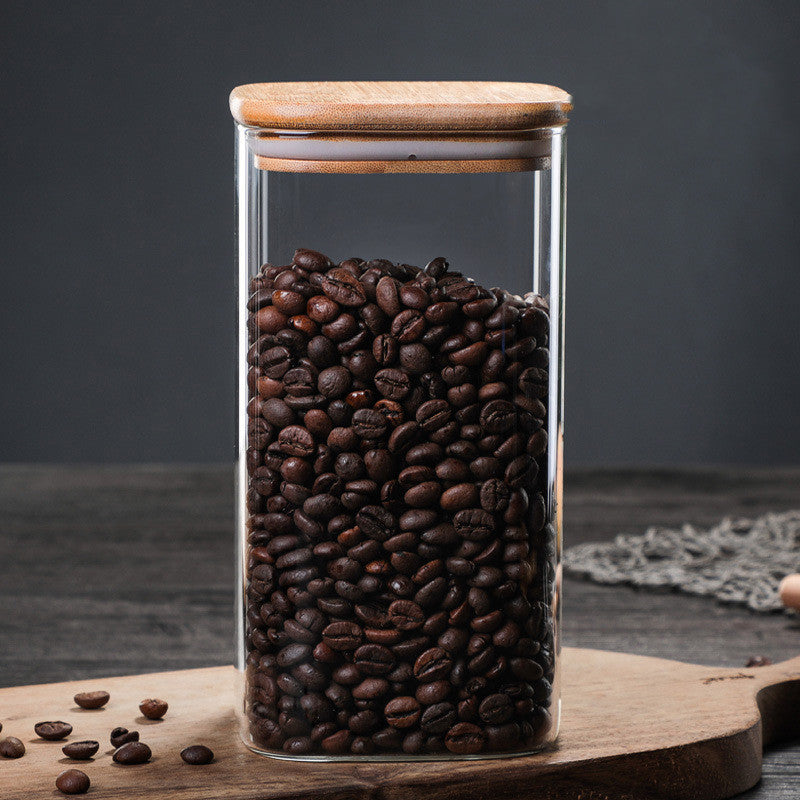 Jar with wooden lid filled with coffee beans on a wooden kitchen surface on a dark grey background. A warm minimalist interior with simple decor and simple design. Storage kitchen jar. 