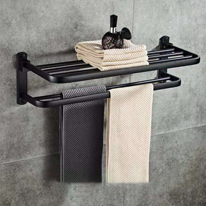 Black towel rack with folded towels on a gray tiled wall. 