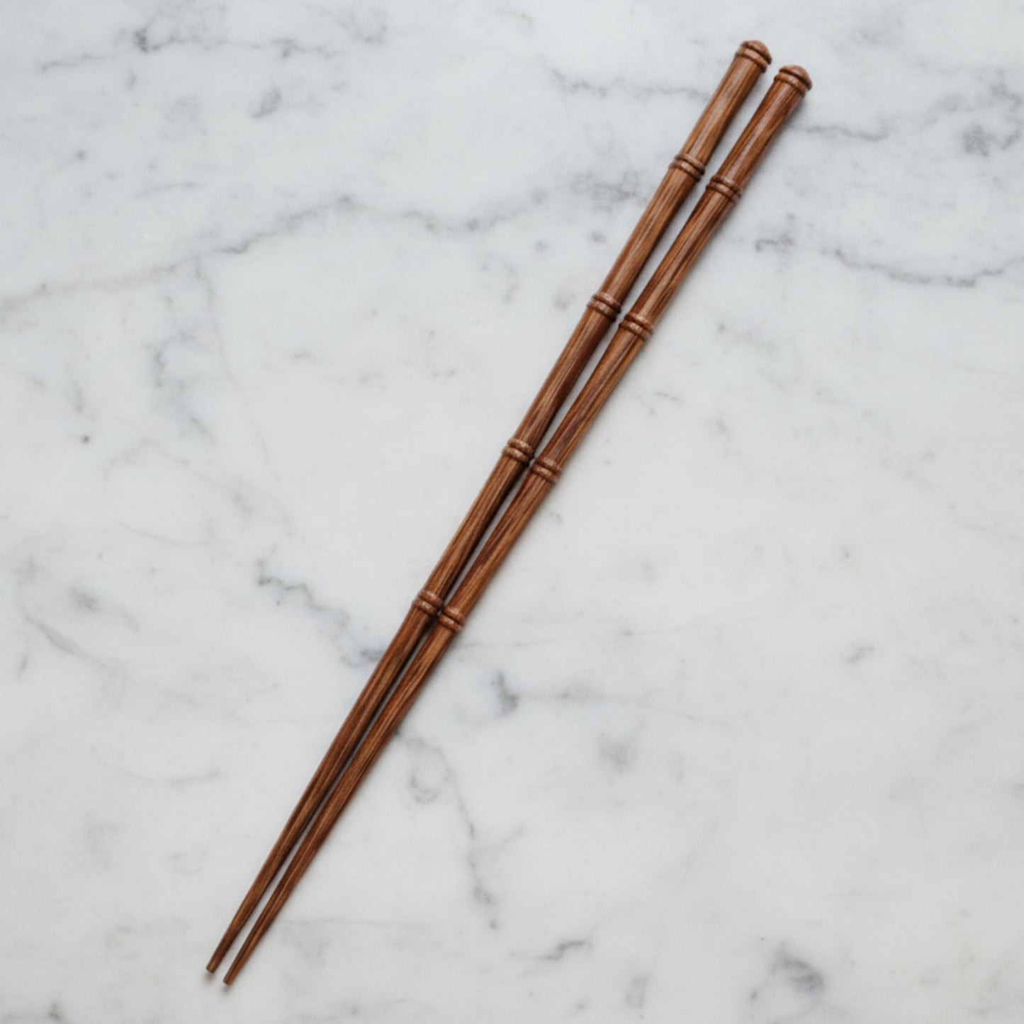 One pair of wooden chopsticks on a marble surface. Natural and pure material and earthy ambience. 