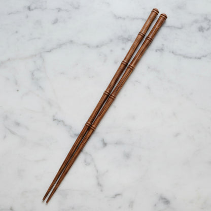 One pair of wooden chopsticks on a marble surface. Natural and pure material and earthy ambience. 