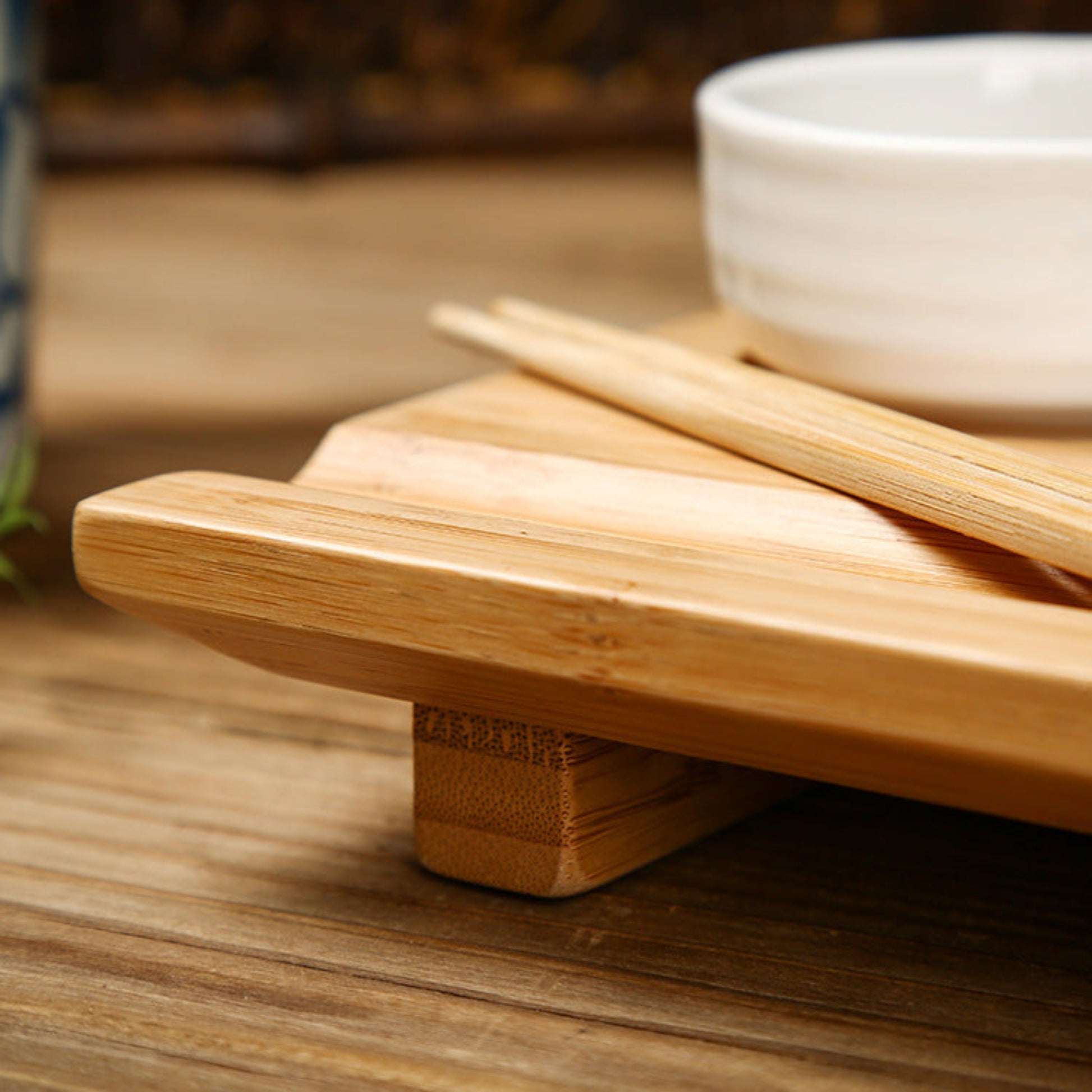A sushi plate with chopsticks on a wooden tray with a white ceramic bowl and a brown background. Natural decor. Minimalist decor piece with warmth and harmony. 
