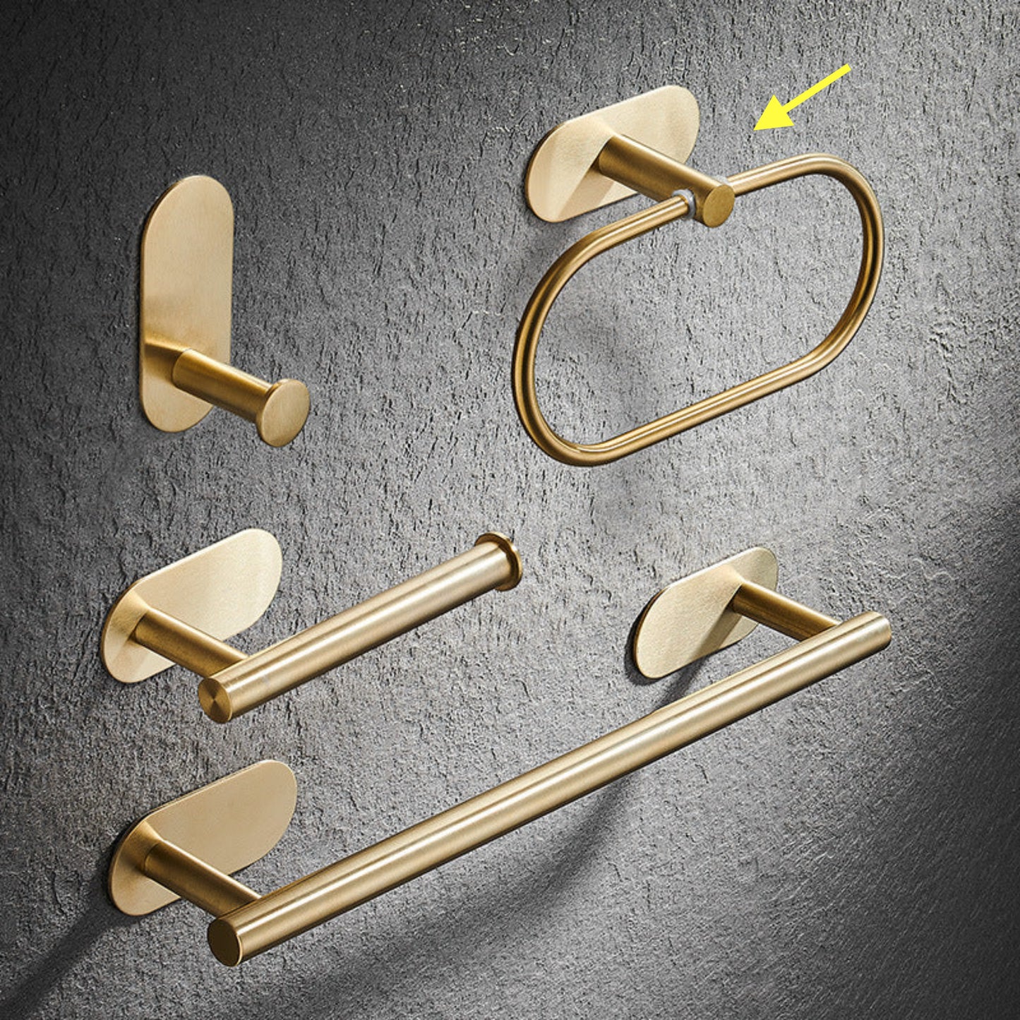 Set of gold bathroom rack including a hook, towel ring, and towel bar on a gray textured background. Stylish golden bathroom rack. Modern bathroom rack, minimalist and timeless pieces for bathroom. 