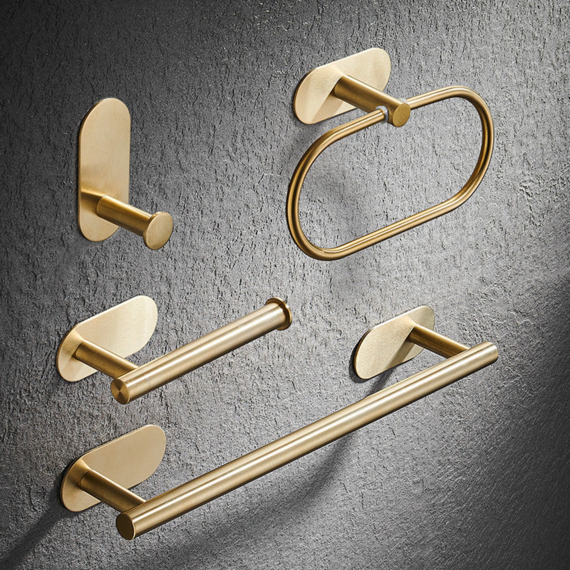Set of gold bathroom fixtures including a hook, towel ring, and towel bar on a gray textured background. Stylish golden bathroom rack. Modern bathroom rack, minimalist and timeless pieces for bathroom. 