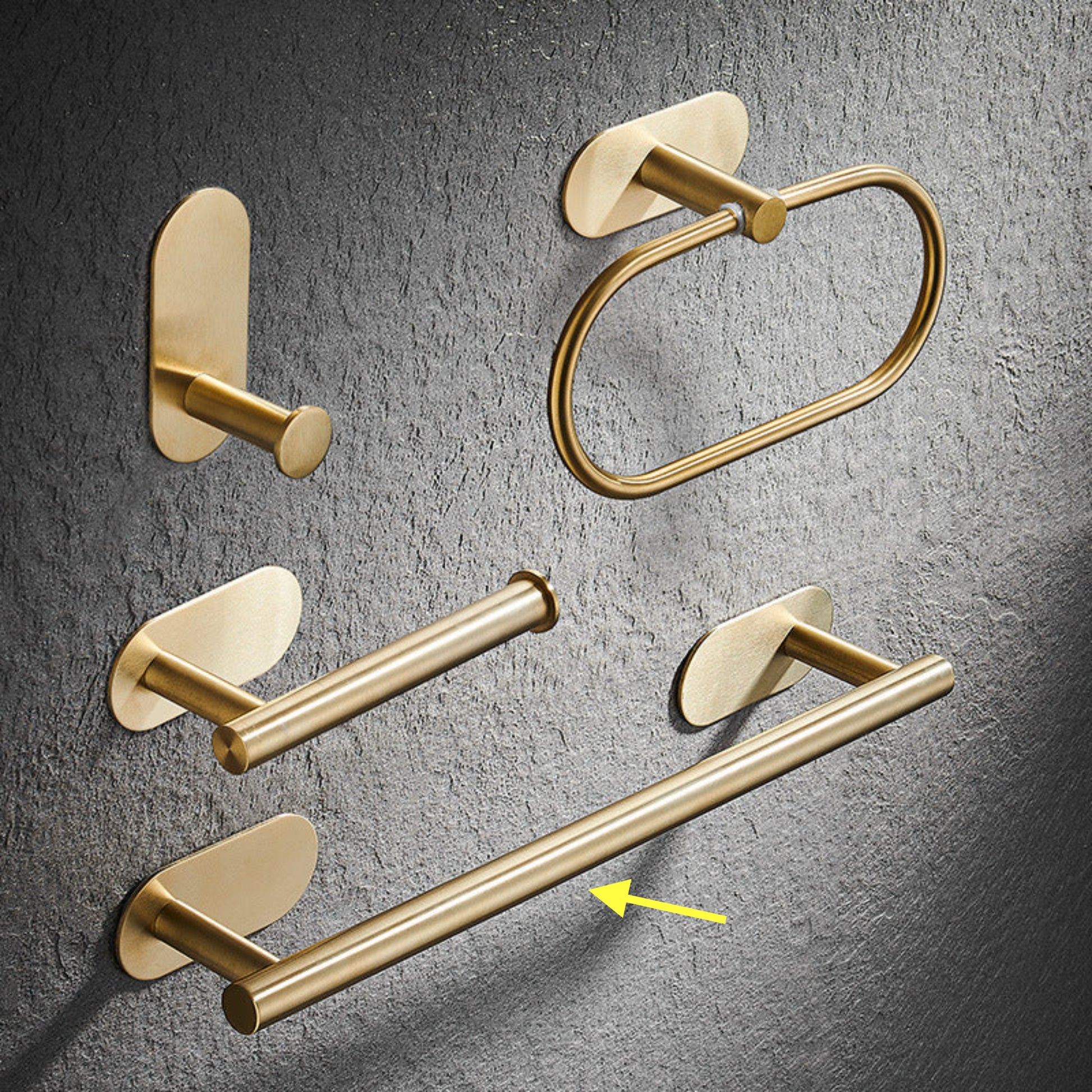 Set of gold bathroom rack including a hook, towel ring, and towel bar on a gray textured background. Stylish golden bathroom rack. Modern bathroom rack, minimalist and timeless pieces for bathroom. 