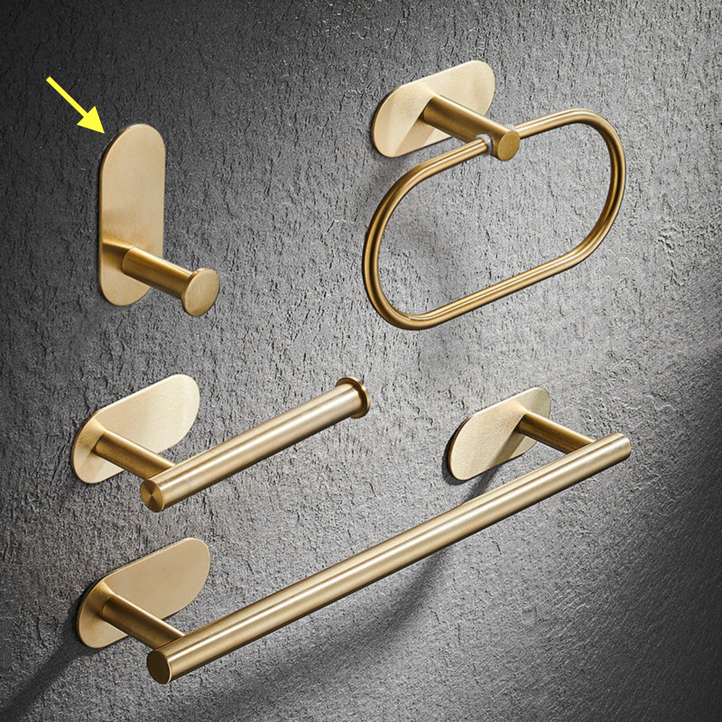 Set of gold bathroom rack including a hook, towel ring, and towel bar on a gray textured background. Stylish golden bathroom rack. Modern bathroom rack, minimalist and timeless pieces for bathroom. 