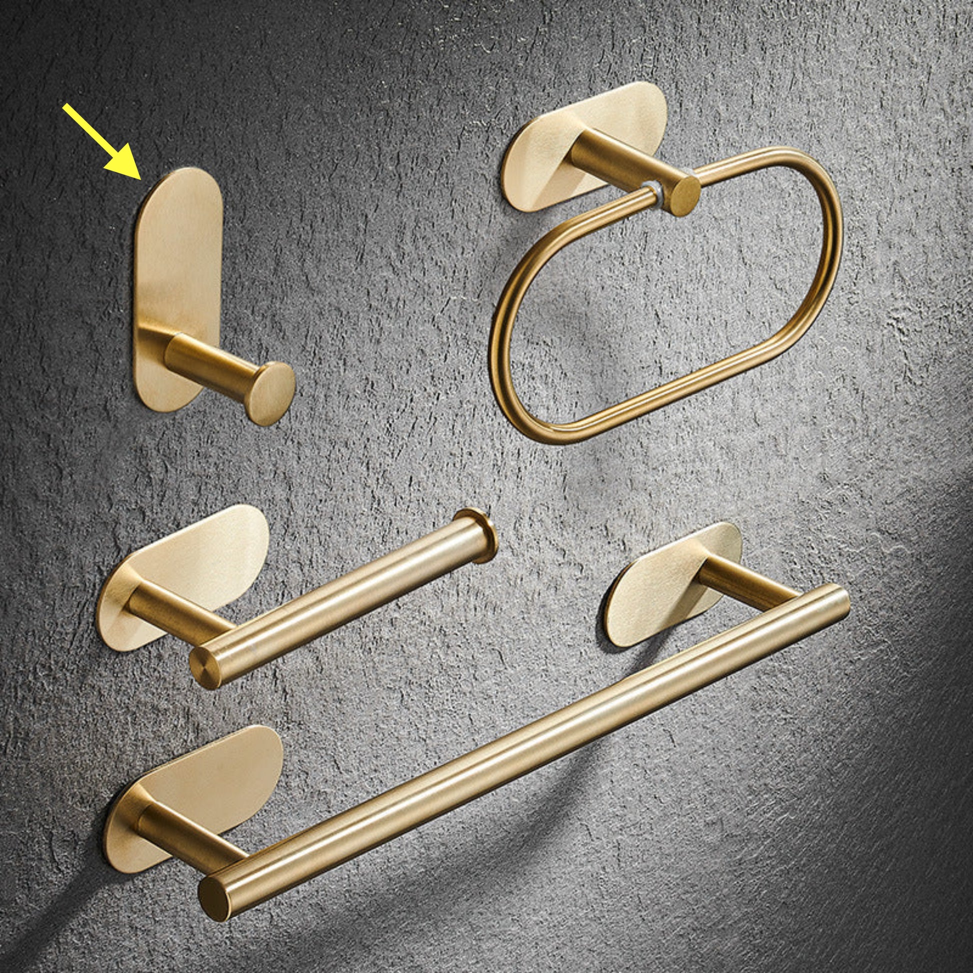 Set of gold bathroom rack including a hook, towel ring, and towel bar on a gray textured background. Stylish golden bathroom rack. Modern bathroom rack, minimalist and timeless pieces for bathroom. 