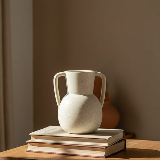 Beige Scandinavian decor inspired ceramic binaural vase on two books and a table. Warm tones. Minimalist interiors.