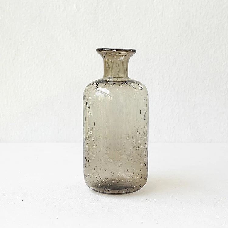 A collection of bubble glass vases in various sizes, with a geometric shape and a translucent stained glass appearance on a white surface and on a white background. 