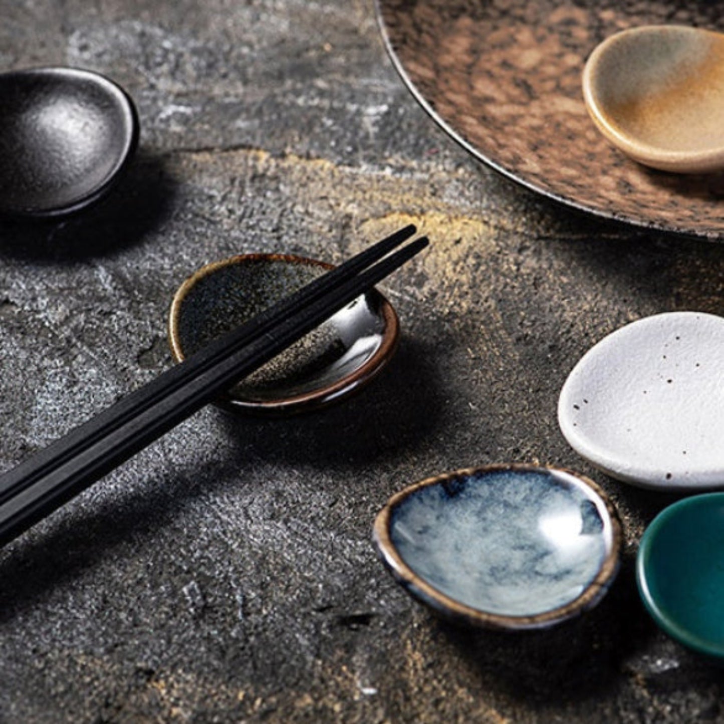 Stylish ceramic chopsticks holder with chopsticks on it, Japanese style on a dark stony surface. modern kitchen accessories, timeless pieces. 