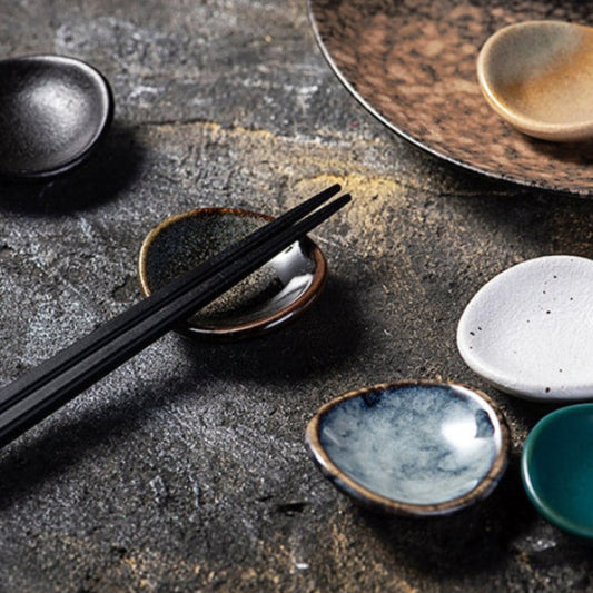 Stylish ceramic chopsticks holder with chopsticks on it, Japanese style on a dark stony surface. modern kitchen accessories, timeless pieces. 