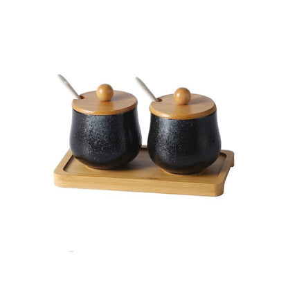A set of ceramic jars with Japanese style designs, featuring a speckled black and pattern on a white background. The jars come with spoons, with wooden lids and are displayed on a wooden tray. 