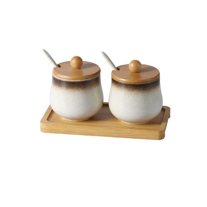 A set of two ceramic jars with Japanese style designs, featuring a speckled brown and white pattern on a white background.  The jars come with wooden lids and are displayed on a wooden tray.