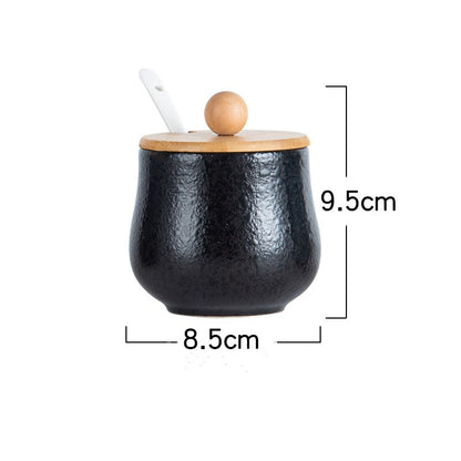 A set of ceramic jars with Japanese style designs, featuring a speckled black pattern on a white background with dimensions. The jar comes with a wooden lid and a white spoon. 