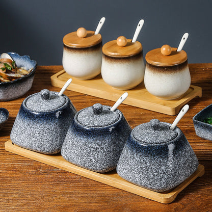 Set of blue and white ceramic containers with wooden lids (only white jars) and spoons on a wooden tray. 