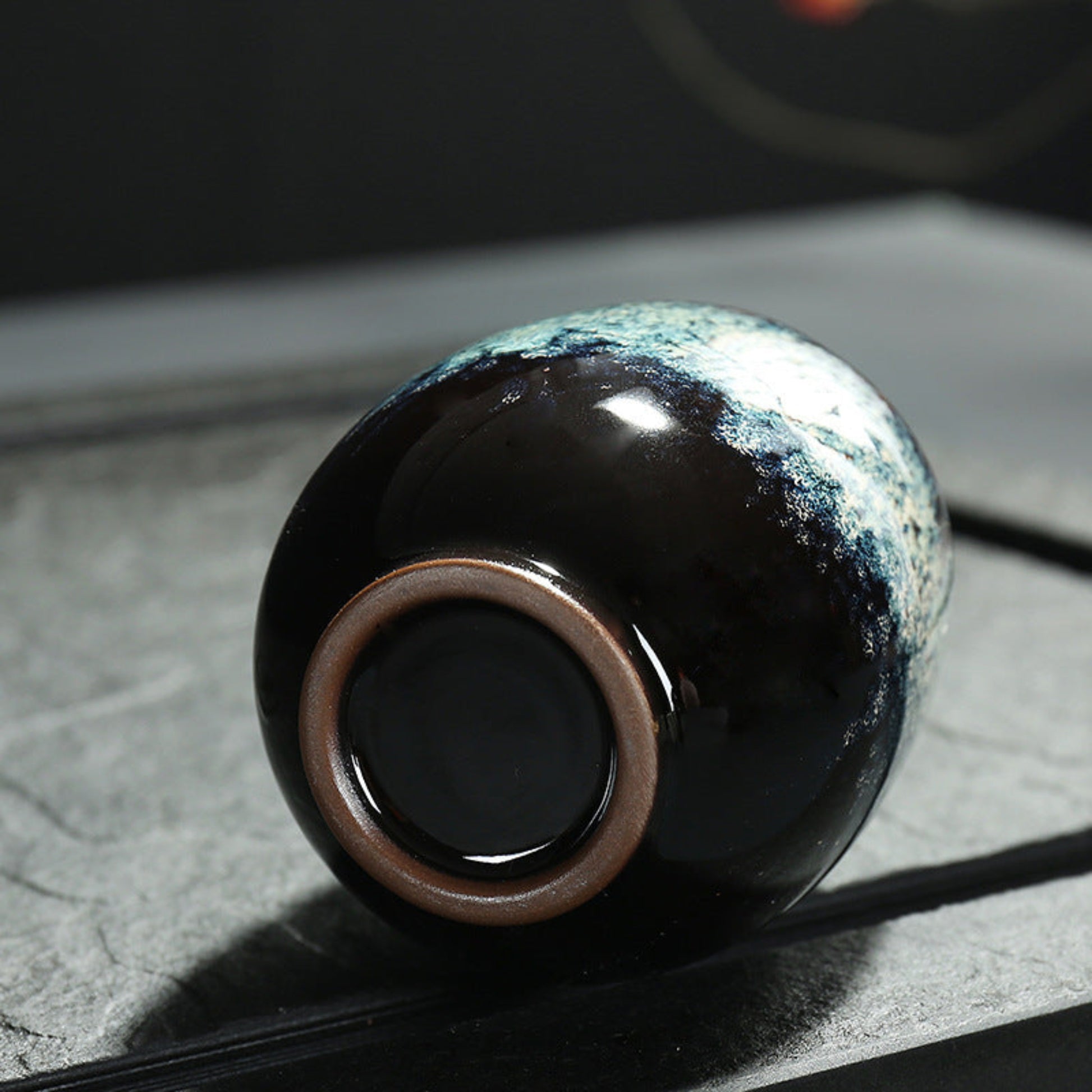 Ceramic cup with unique glaze pattern on a textured surface. Natural and earthy ambience from a close up. 