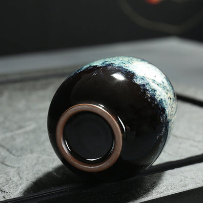 Ceramic cup with unique glaze pattern on a textured surface. Natural and earthy ambience from a close up. 