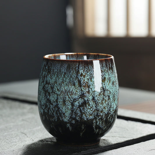 Turquoise ceramic cup with textured surface on a stone surface. Natural and earthy ambience. 