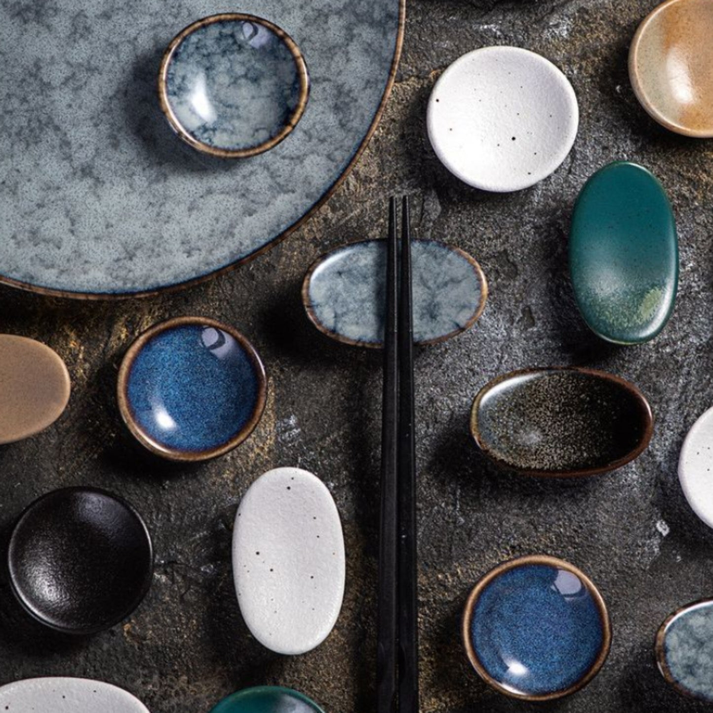 Collection of ceramic bowls with various colors and textures on a dark surface.
Stylish ceramic chopsticks holder. Modern kitchen accessories, timeless pieces. 