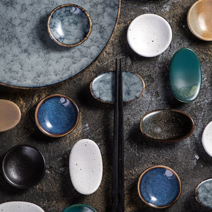 Collection of ceramic bowls with various colors and textures on a dark surface.
Stylish ceramic chopsticks holder. Modern kitchen accessories, timeless pieces. 