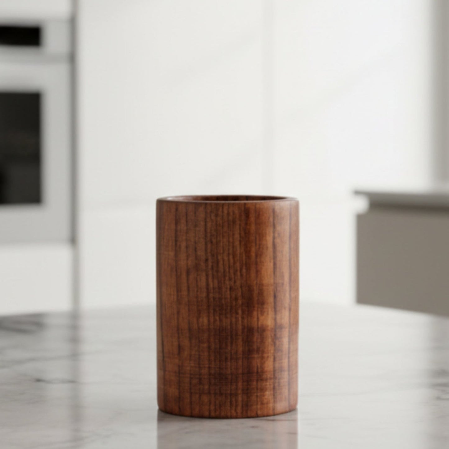 Wooden storage bucket for kitchen cooking spatula on a grey marble surface with a blurred bright background. 