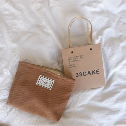 Brown fabric pouch and cardboard tote bag on a bed sheet. Minimalist accessories inspired by natural materials and Scandinavian design. 