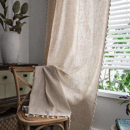 Beige curtain draped over a chair with a plant and window in the background. Natural decor styling curtain for calm and modern interiors.