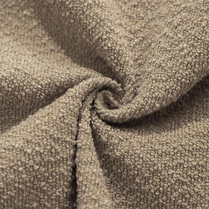 Close-up of beige textured fabric with a slight roll of the boucle pillow cover. 