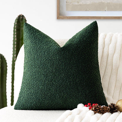 A green Decorative Boucle Pillow Cover with a textured surface displayed on a neutral background and a cactus in the background. Warm and cozy decor ambience. 