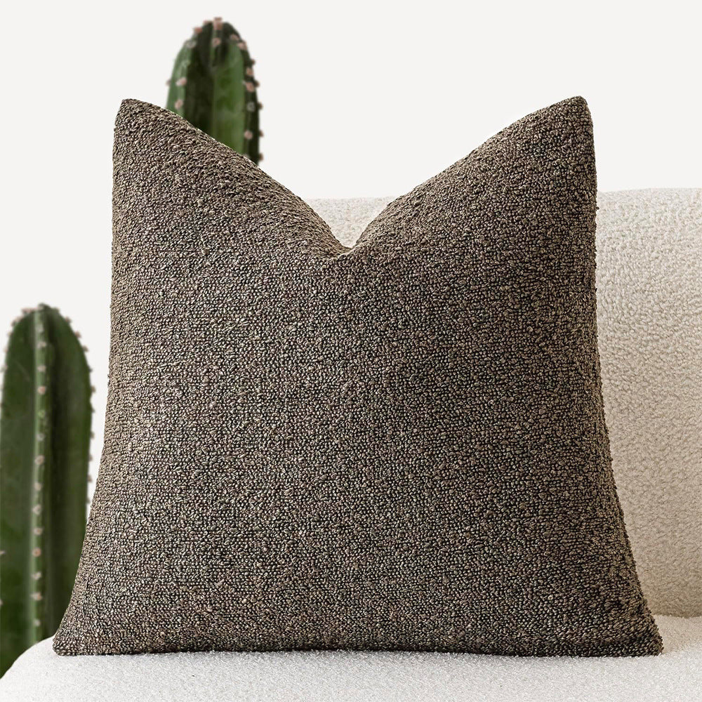 A light gray Decorative Boucle Pillow Cover with a textured surface displayed on a neutral background and a cactus in the background. Warm and cozy decor ambience. 