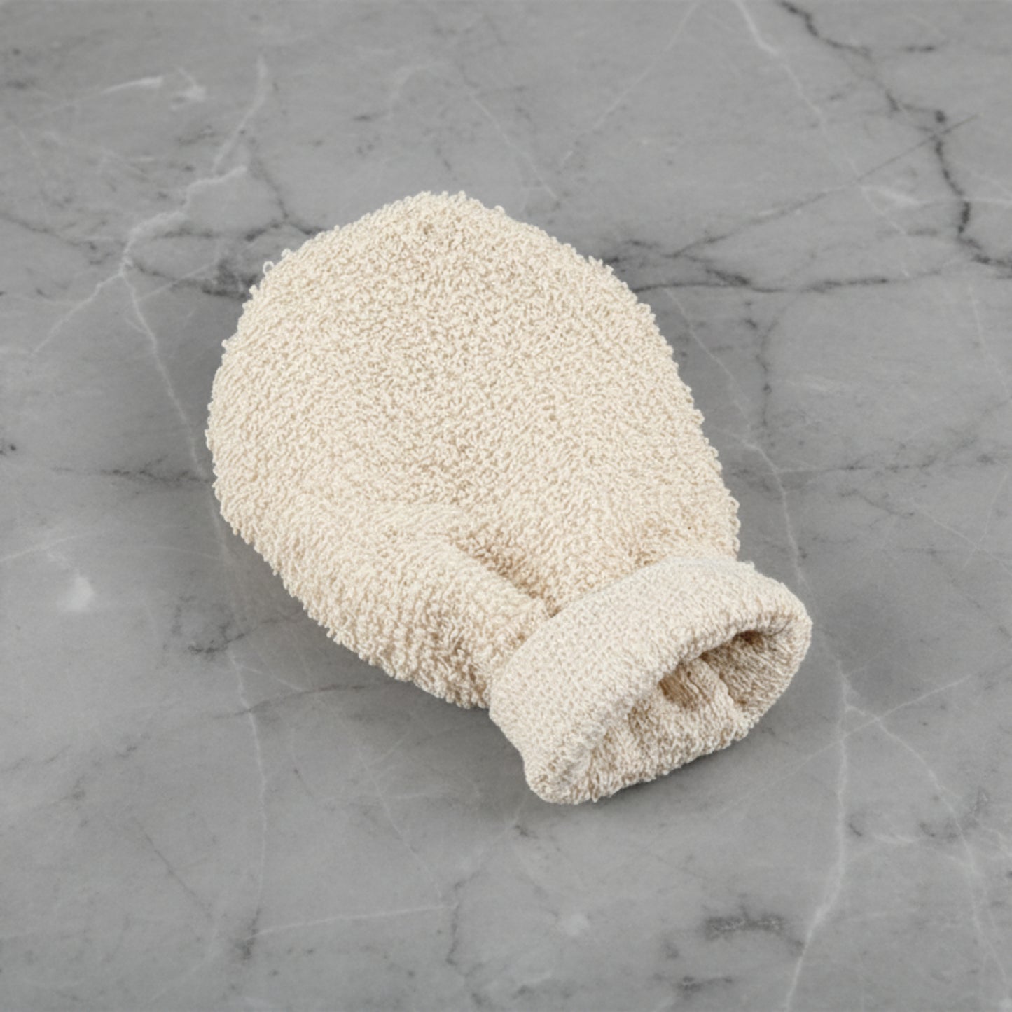 Beige scrubbing glove on a grey marble surface.  Natural home decor designed with warm earthy tones and organic materials.   