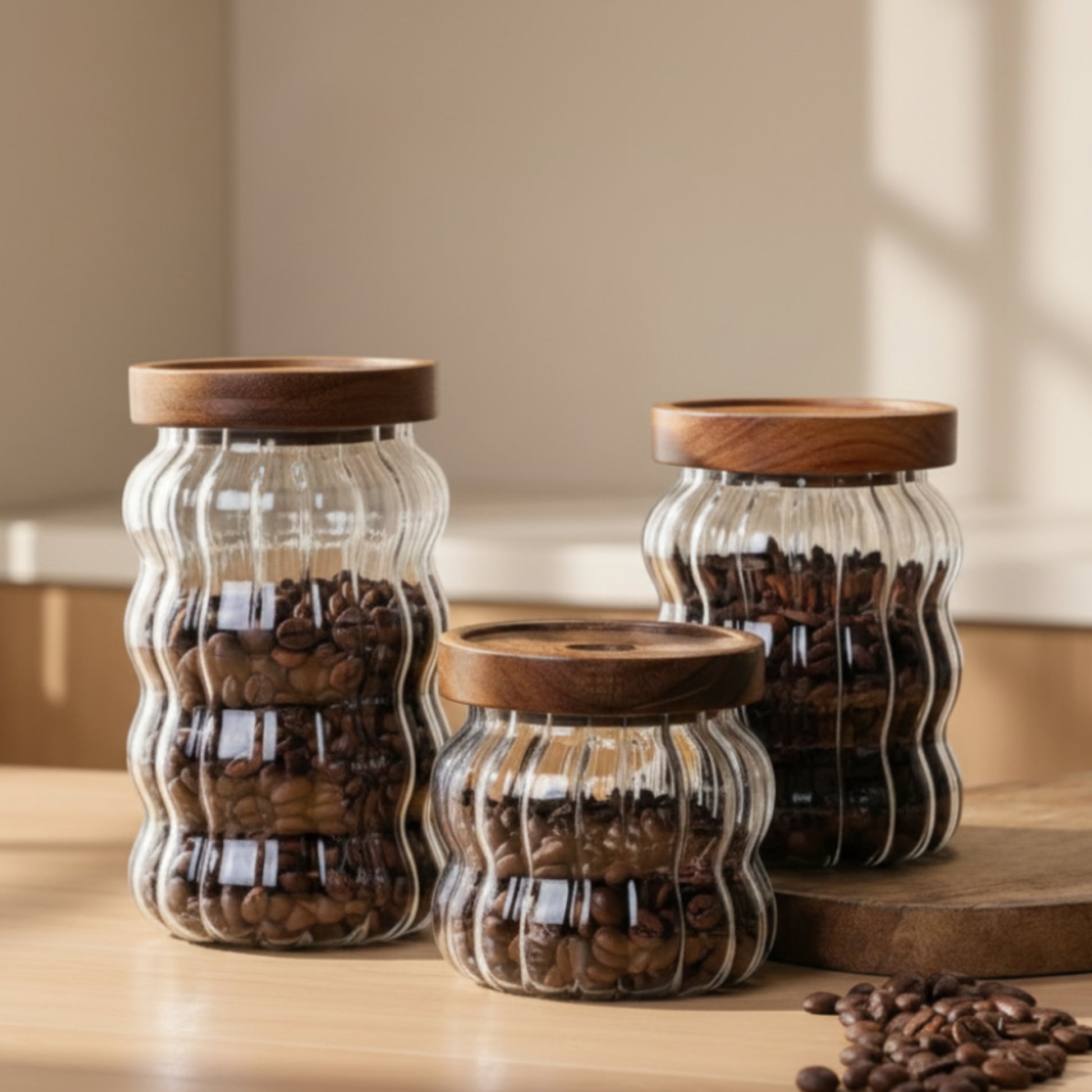 Three glass jars with wooden lids filled with coffee beans on a light surface on a wooden table. Scandinavian kitchen decor inspired. Simplicity, natural materials, and warm tones in the background. 