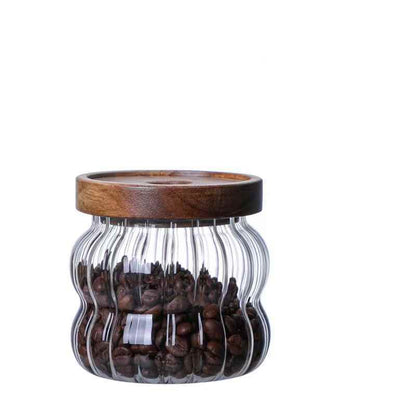 One small glass jar with wooden lid, filled with coffee beans and on a white background. Scandinavian kitchen decor inspired. Simplicity, natural materials, earthy, warm, pure. 