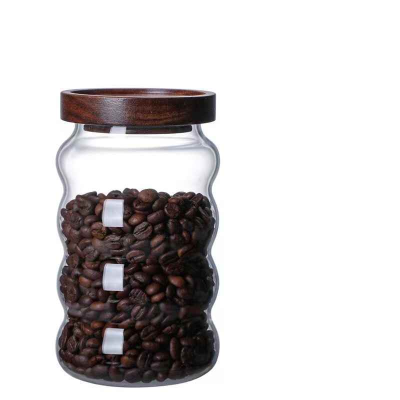 One large glass jar with wooden lid, filled with coffee beans and on a white background. Scandinavian kitchen decor inspired. Simplicity, natural materials, earthy, warm, pure. 