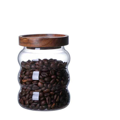 One glass jar with wooden lid, filled with coffee beans and on a white background. Scandinavian kitchen decor inspired. Simplicity, natural materials, earthy, warm, pure. 
