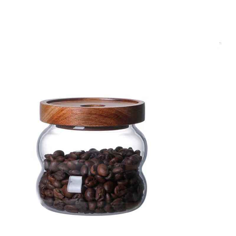 One glass jar with wooden lid, filled with coffee beans and on a white background. Scandinavian kitchen decor inspired. Simplicity, natural materials, earthy, warm, pure. 