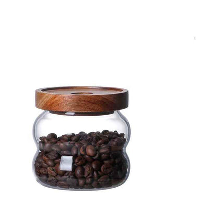 One glass jar with wooden lid, filled with coffee beans and on a white background. Scandinavian kitchen decor inspired. Simplicity, natural materials, earthy, warm, pure. 