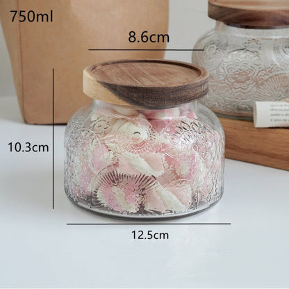 Glass jar with wooden lid and sweet contents, labeled with dimensions. Earthy look and feel with a modern touch. 