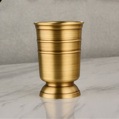 A set of gold-colored copper bathroom accessories including a toothbrush holder, soap dispenser, tumbler, and a tray, displayed on a white surface. Stylish golden bathroom decor designed to elevate every bathroom space. 