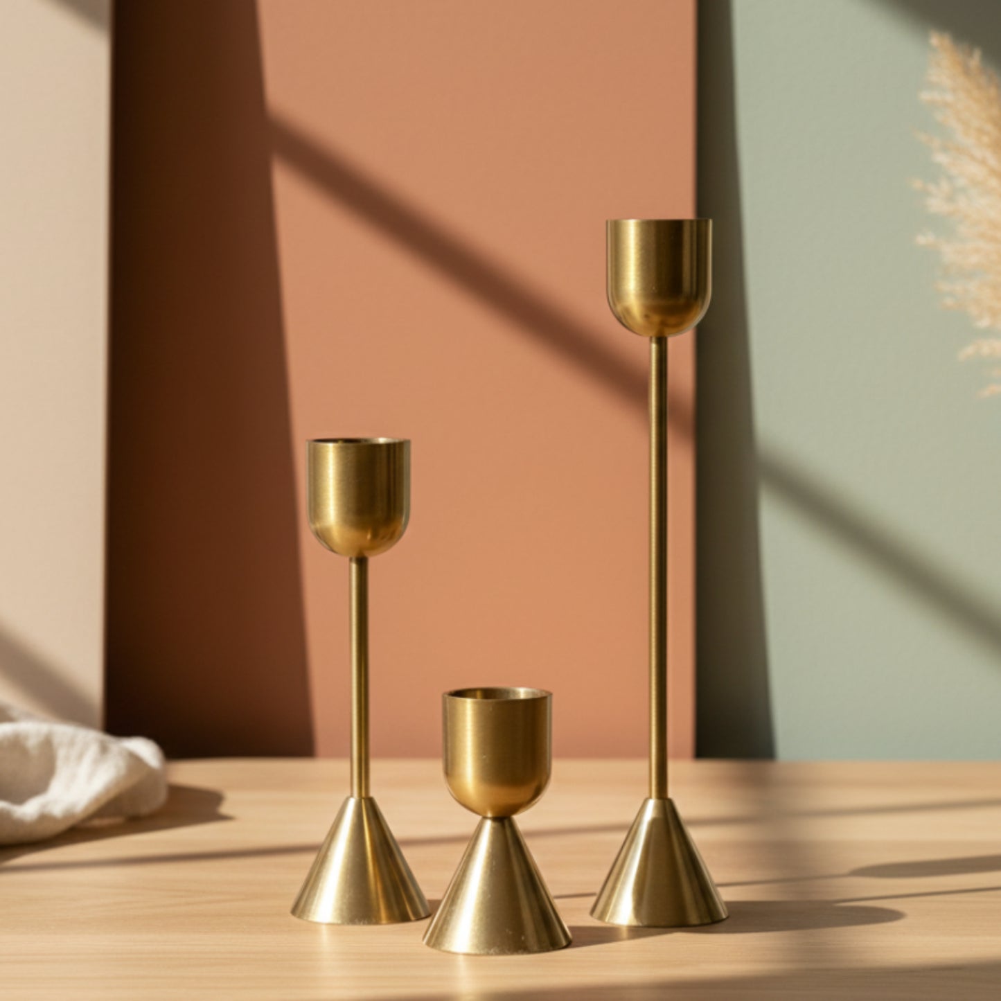 Set of three gold candle holders on a wooden table and a warm and earthy background. Minimalist home decor. Timeless design. Modern home decor.  